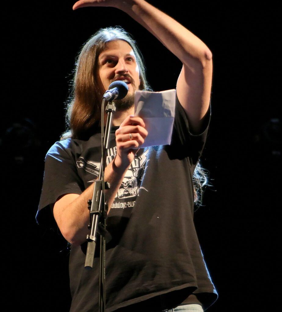 Michael Goehre - Mann mit Textblatt vor einem Mikrofon beim Poetry Slam